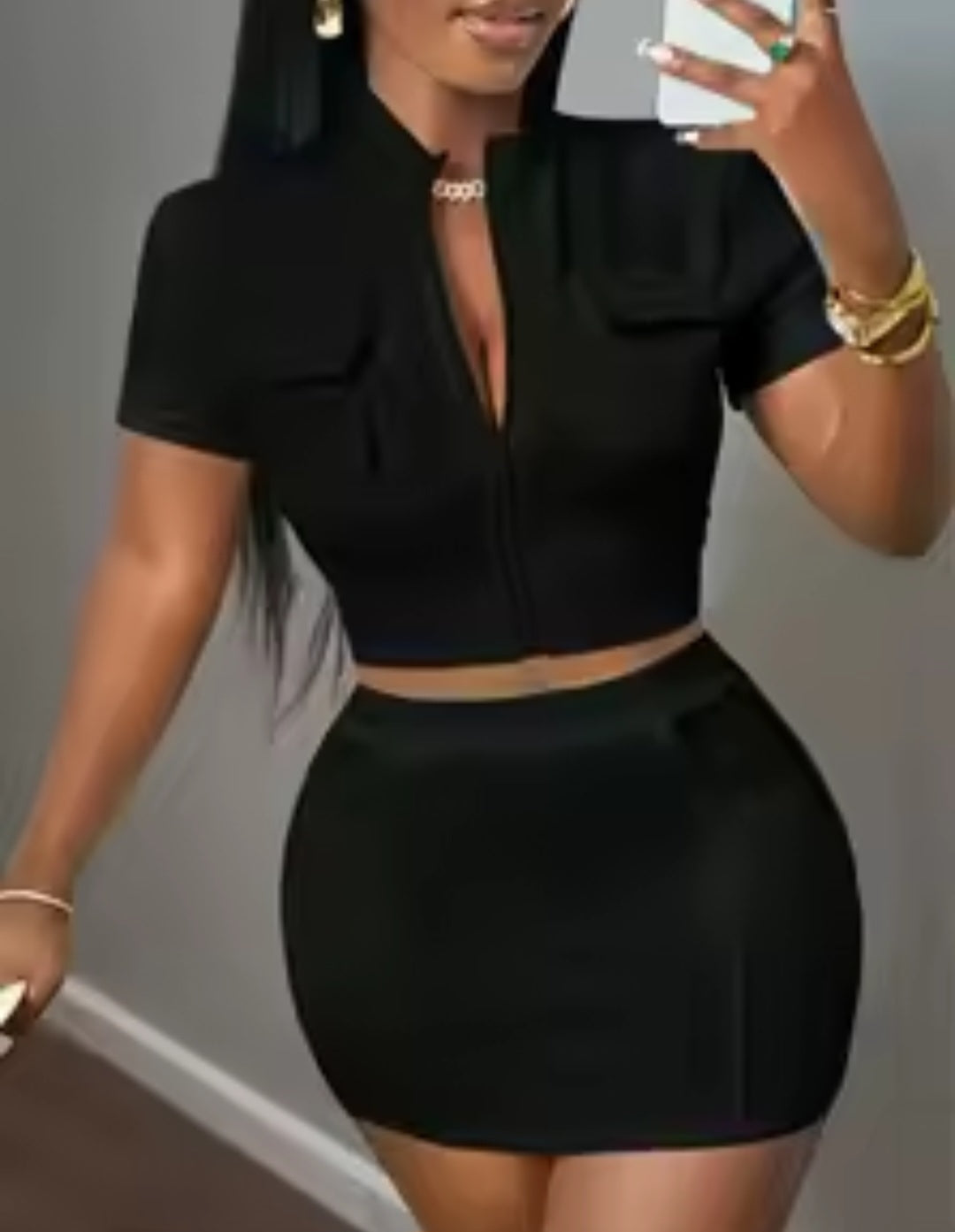 Person wearing a black outfit with a high neckline and short sleeves against a neutral background