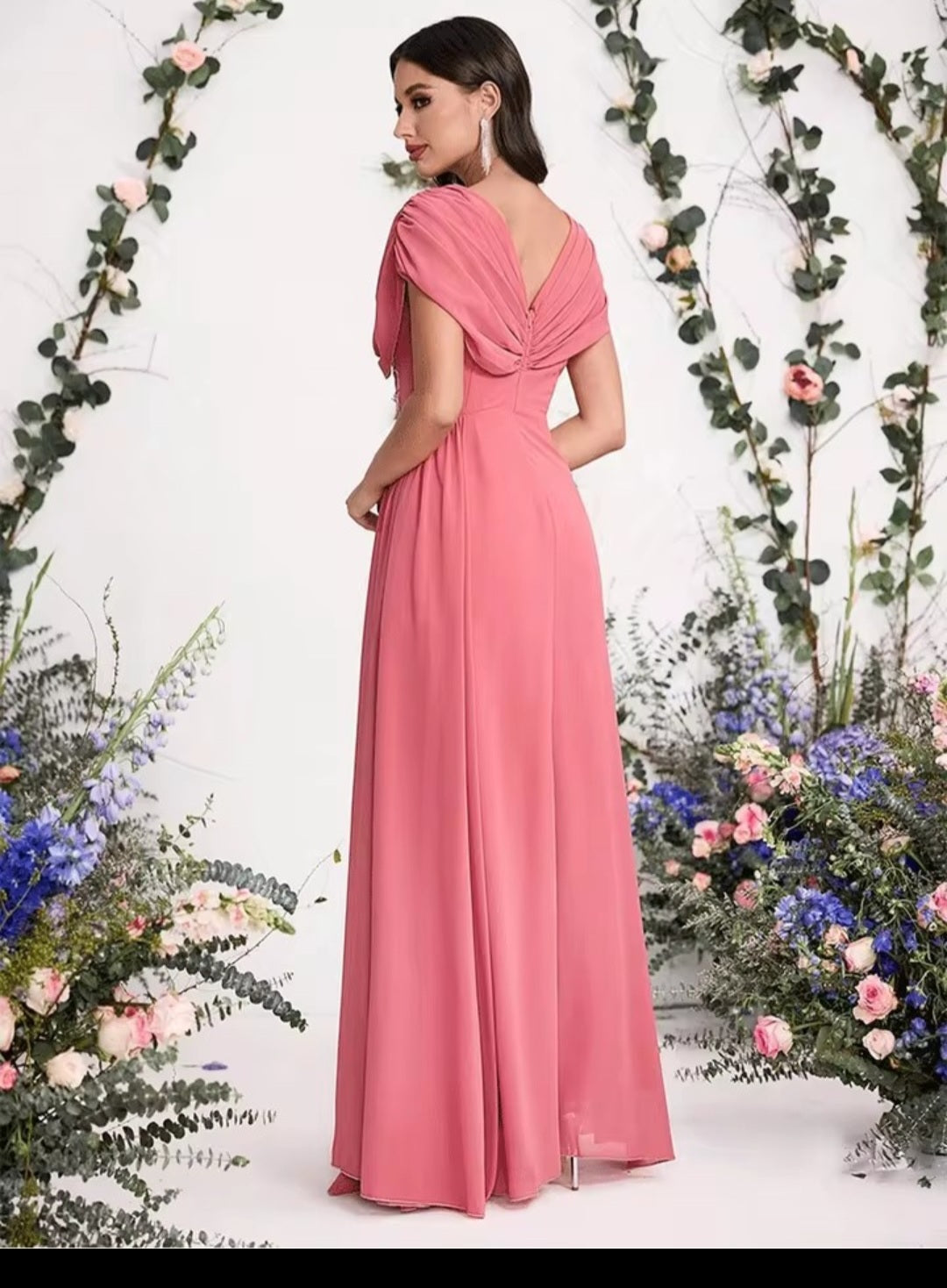 Woman in a pink gown standing in front of floral decorations