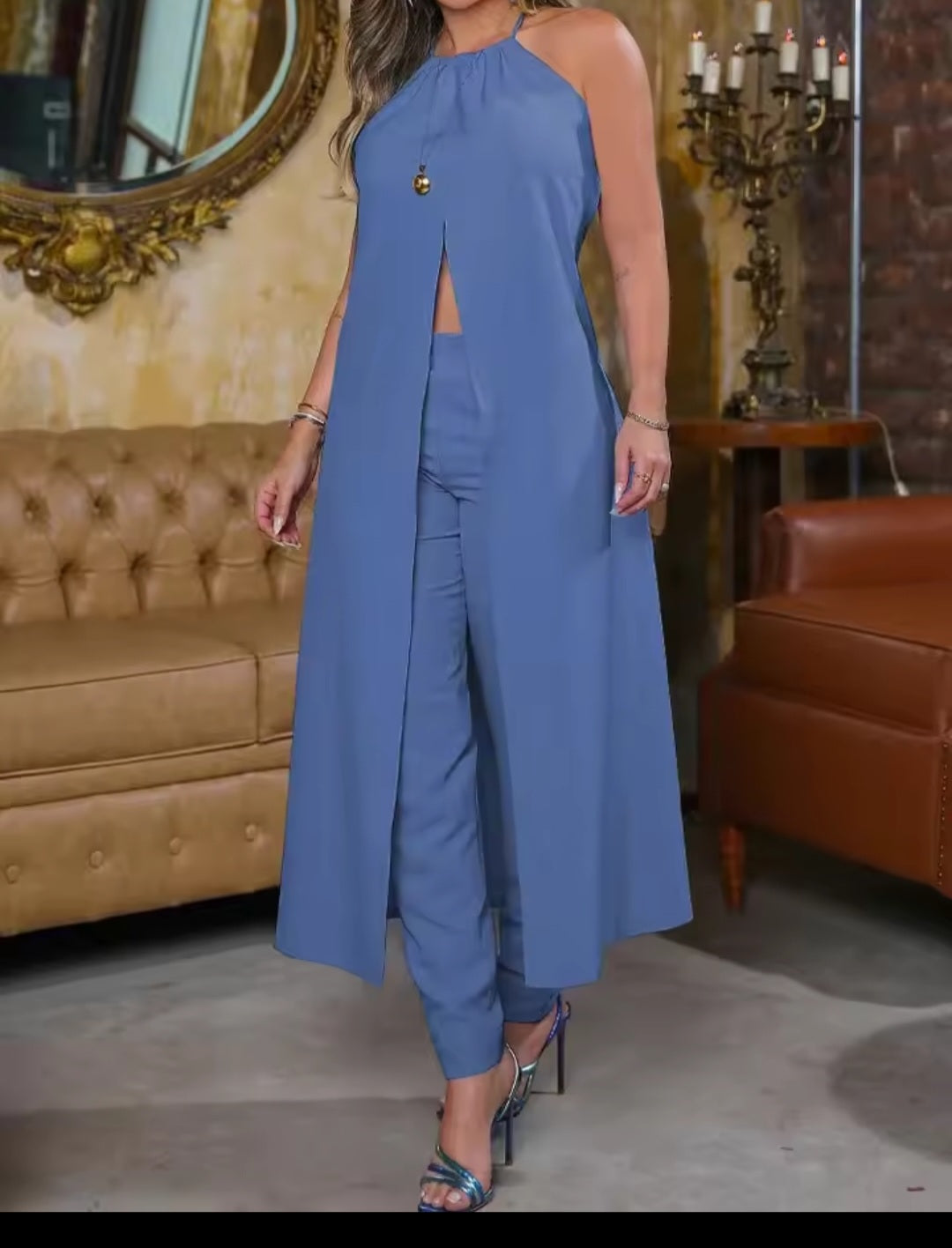 Woman wearing a blue jumpsuit in an elegant room with a mirror and sofa.