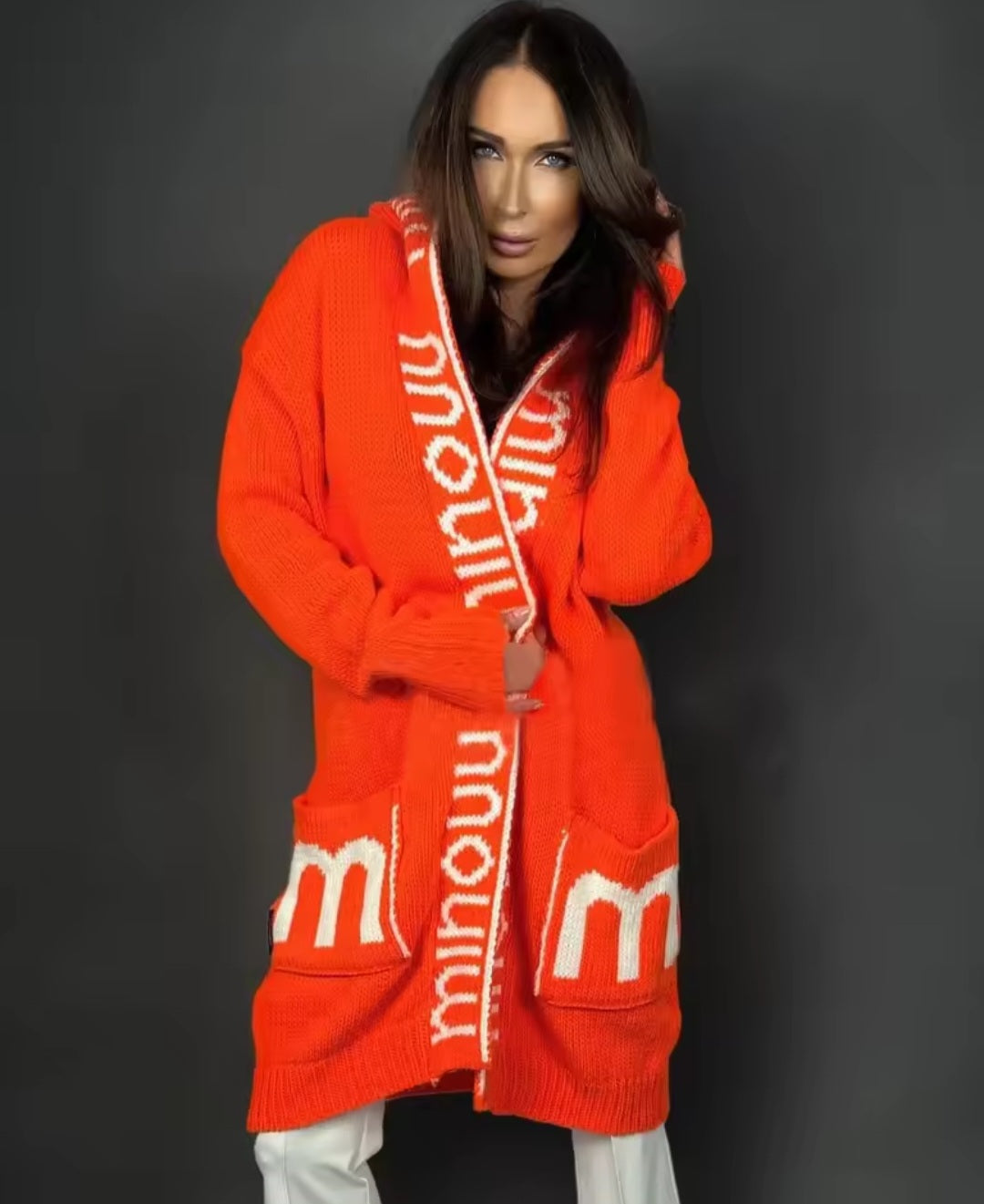 Person wearing a bright orange robe with 'minou' branding on a dark background