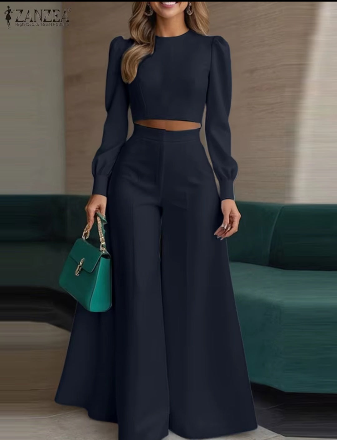 Woman in a navy outfit holding a green handbag in an indoor setting