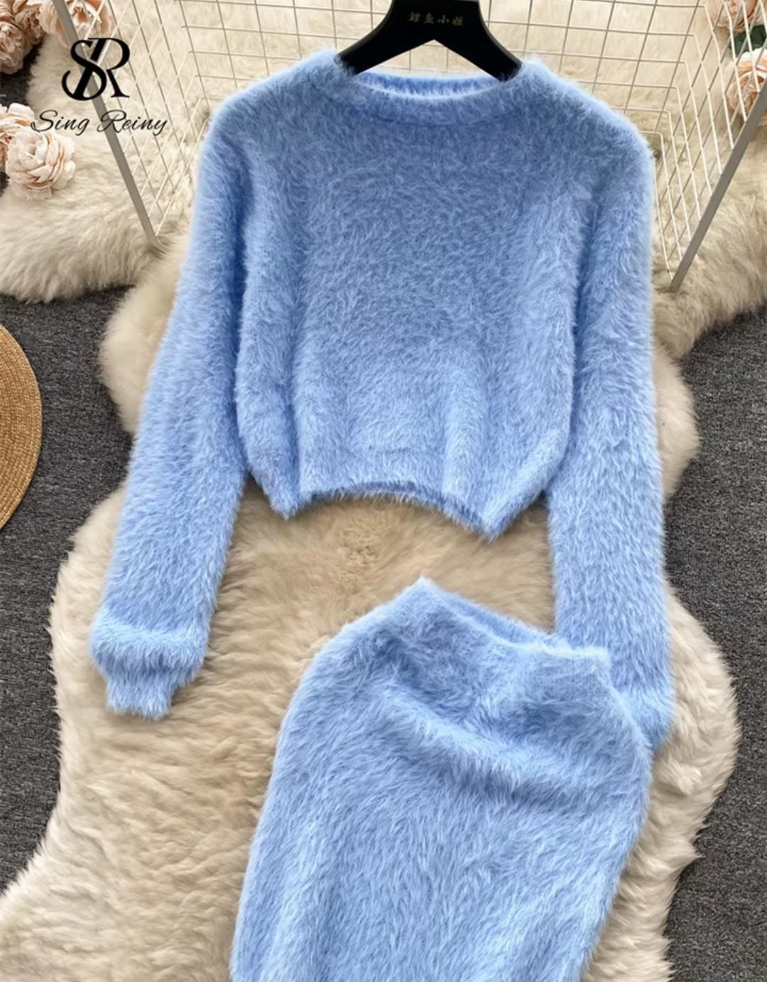 Light blue fuzzy sweater on a hanger with a textured surface background