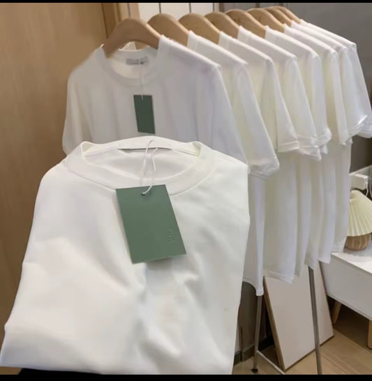 White shirts with tags on hangers against a neutral background