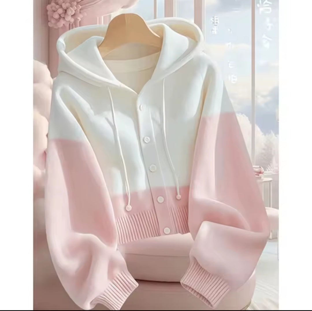 White and pink hoodie on a hanger with a blurred background