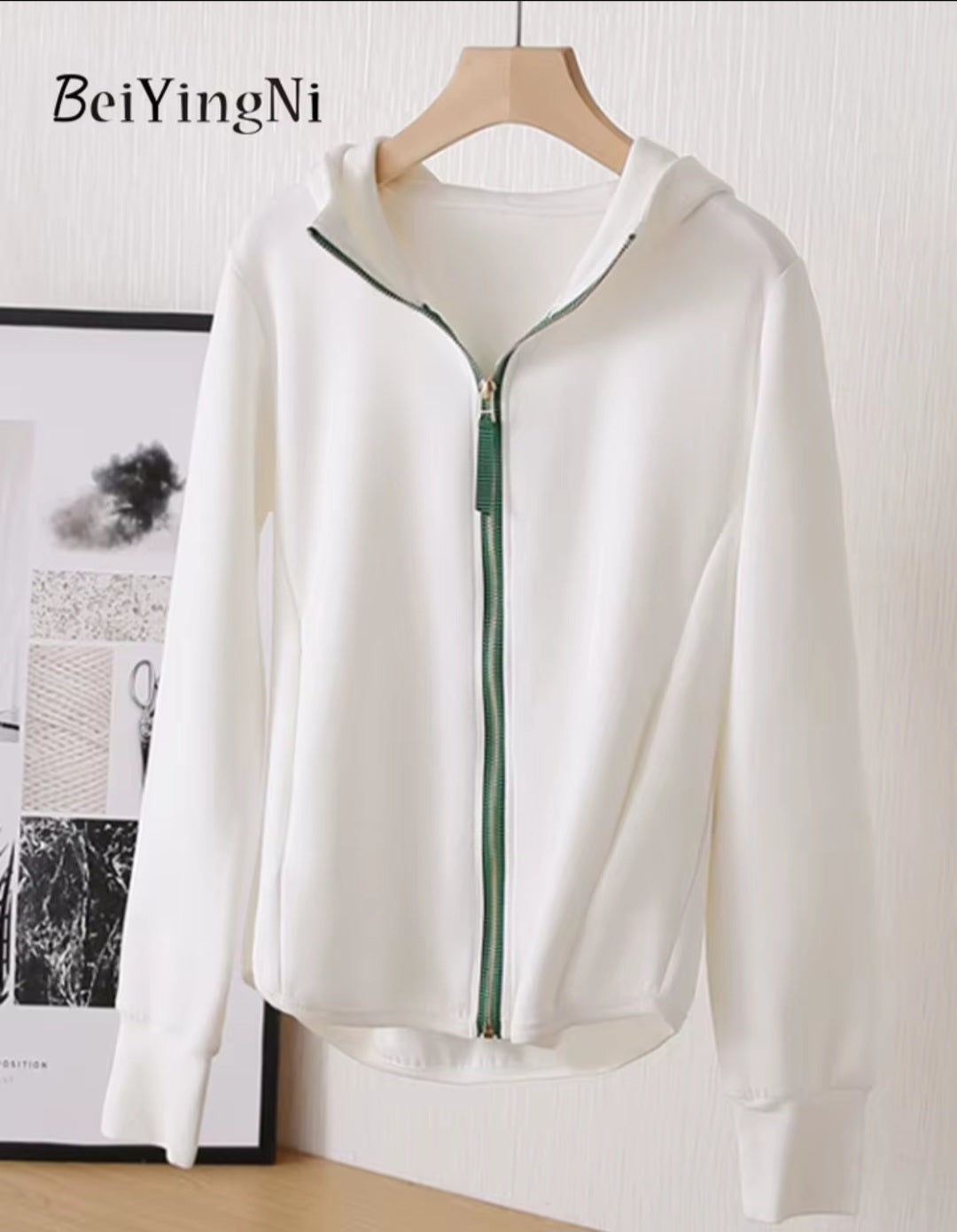 White zip-up hoodie on a hanger with a minimal background