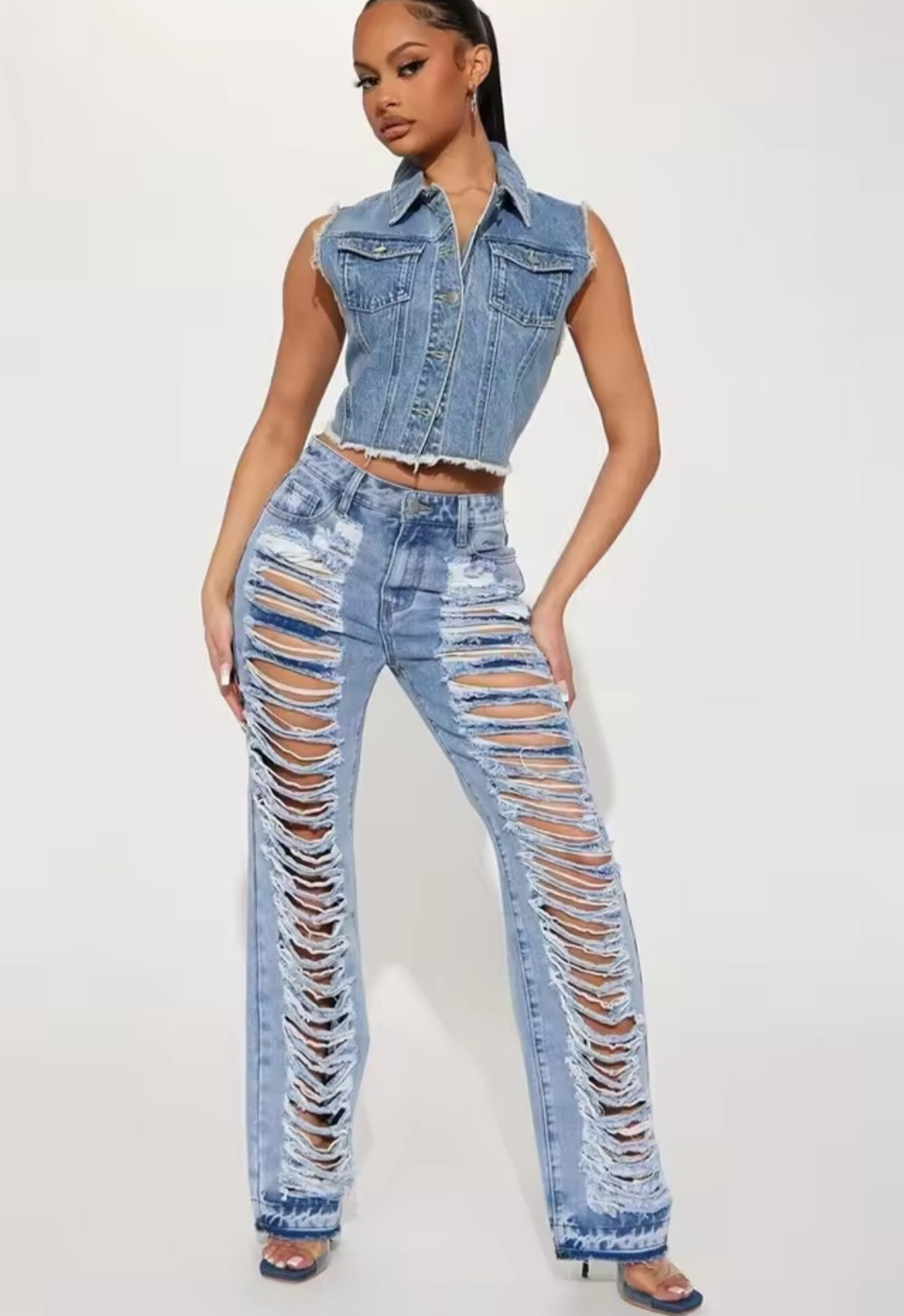 Woman wearing a denim vest and ripped jeans on a white background