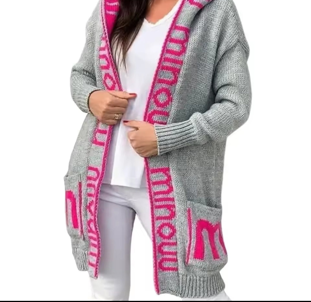 Gray cardigan with pink lettering over a white outfit on a white background