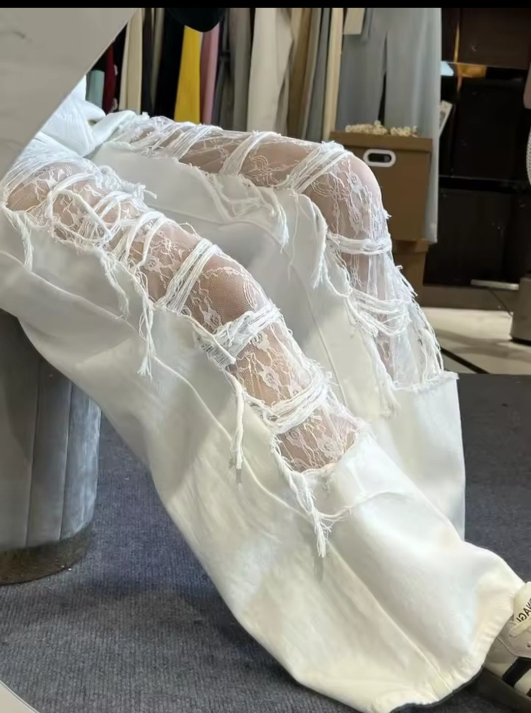 White pants with sheer lace detailing on a clothing rack.