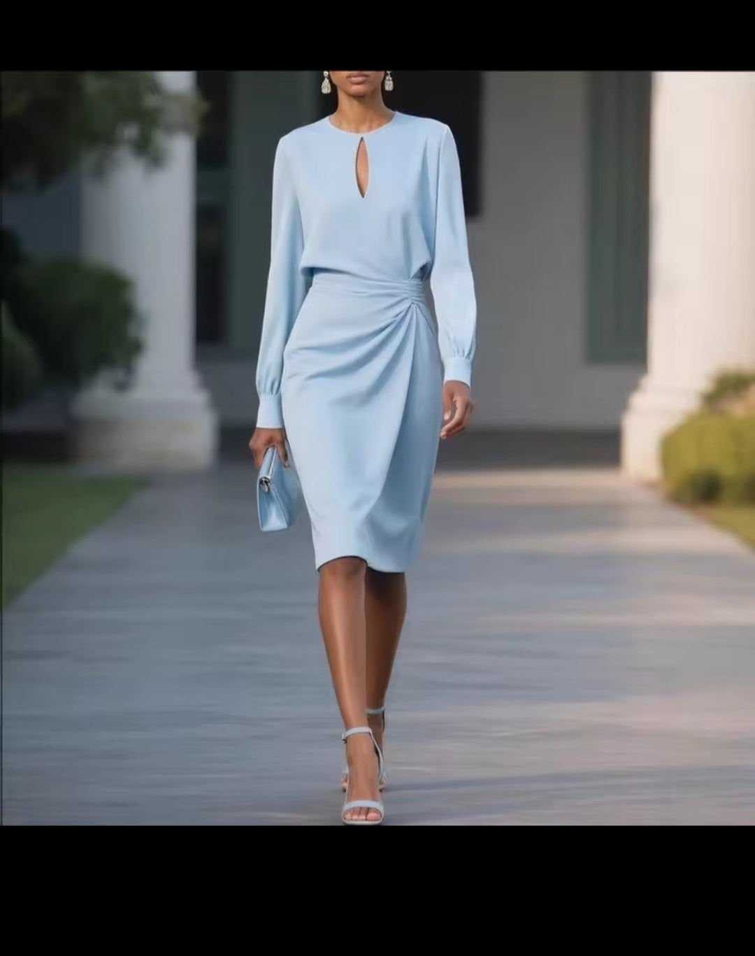 Woman in a light blue dress walking outdoors with columns in the background
