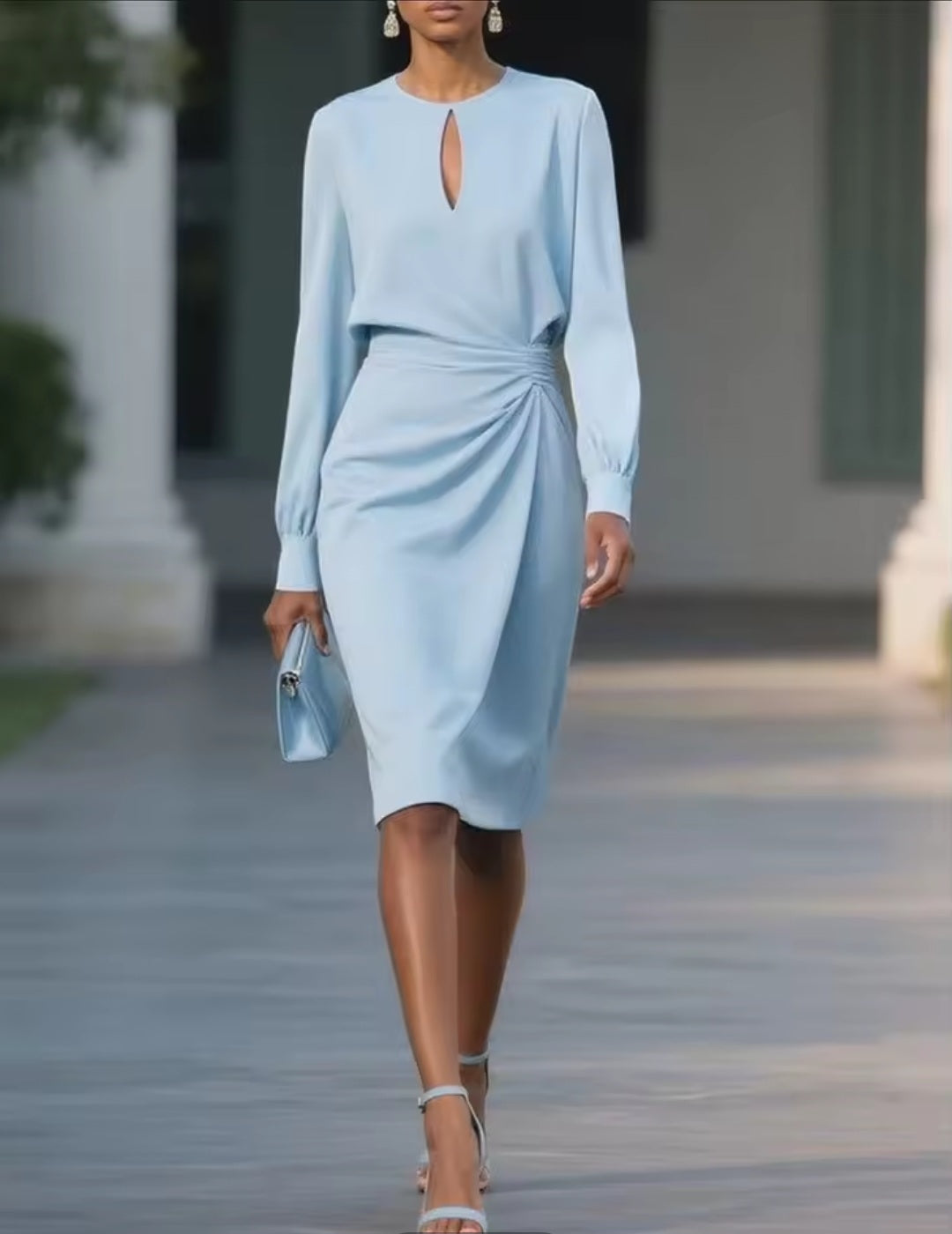 Woman wearing a light blue dress walking outdoors with columns in the background