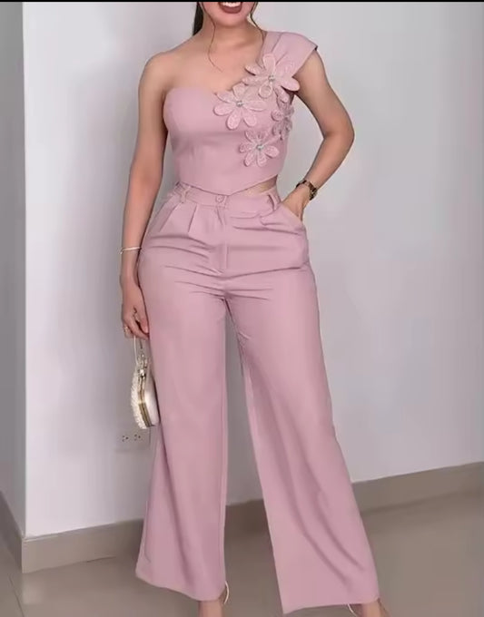 Woman wearing a pink one-shoulder outfit with floral details against a plain background