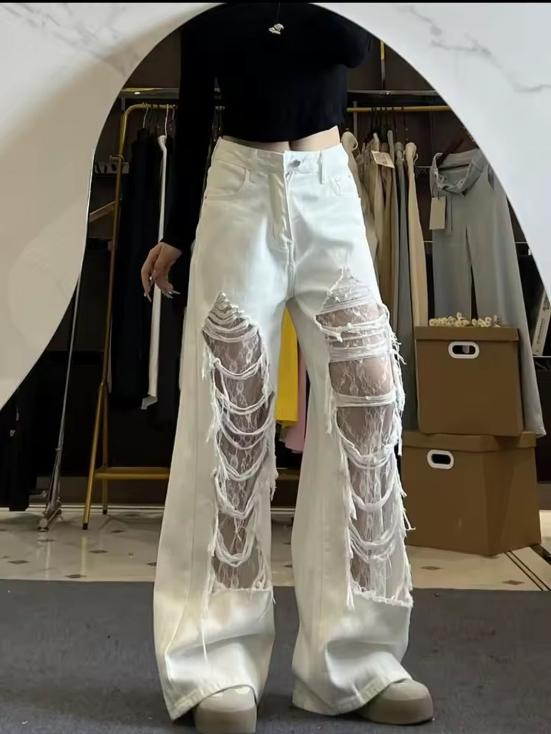 White jeans with sheer panels worn by a person in a clothing store.
