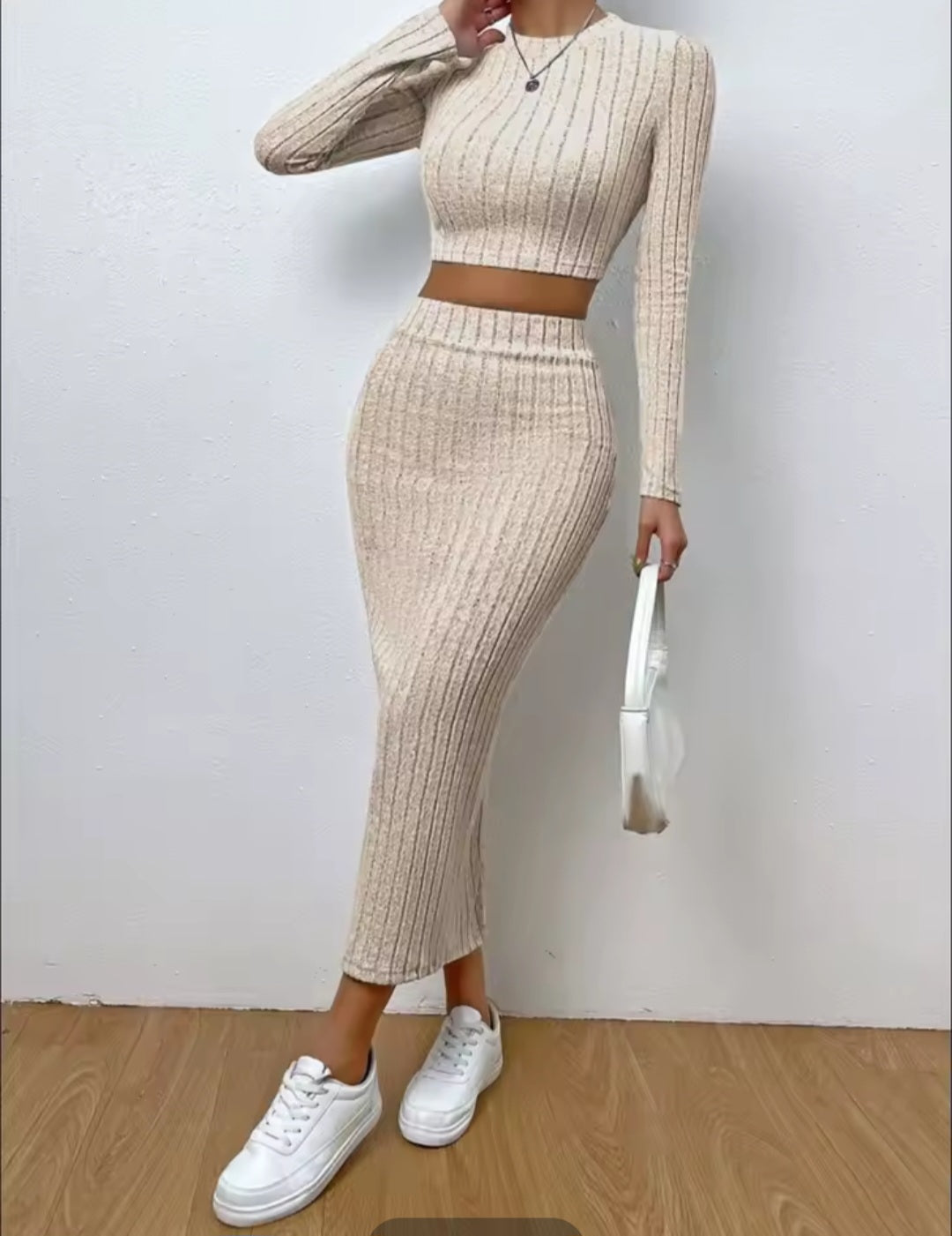 Person wearing a beige ribbed knit two-piece set with white sneakers against a plain background