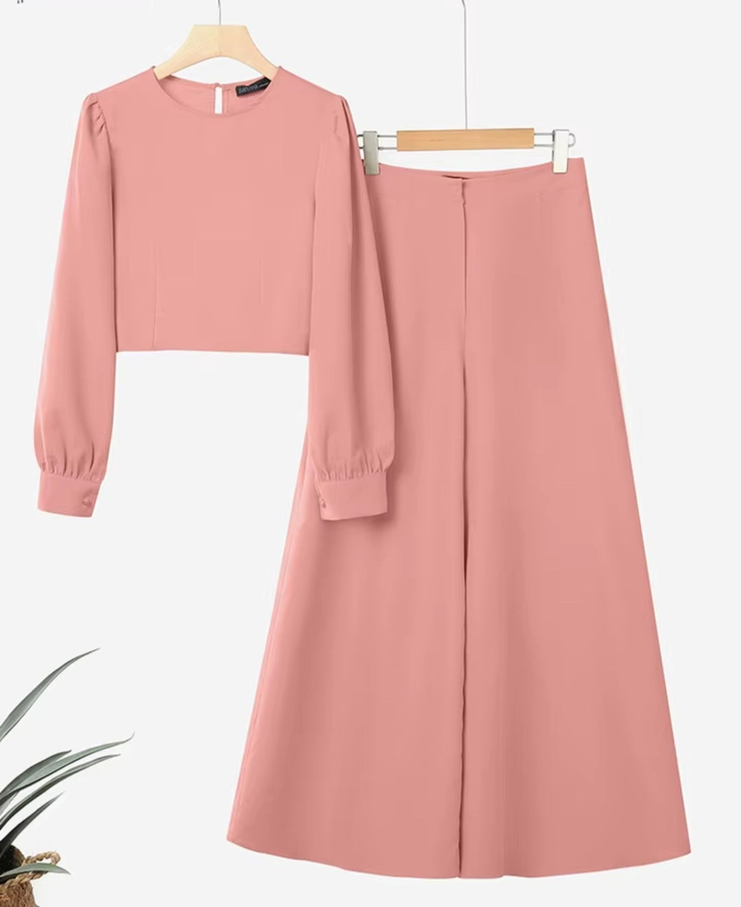 Pink long-sleeve top and skirt set on hangers with a white background